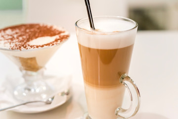coffee latte with frothy milk in tall glass, rustic style, white background