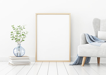Poster mockup with vertical frame standing on floor in living room interior with armchair and branches in blue vase on empty white wall background. 3D rendering, illustration.
