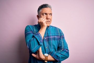 Obraz premium Middle age handsome grey-haired man wearing casual shirt over isolated pink background looking stressed and nervous with hands on mouth biting nails. Anxiety problem.