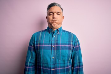 Middle age handsome grey-haired man wearing casual shirt over isolated pink background puffing cheeks with funny face. Mouth inflated with air, crazy expression.