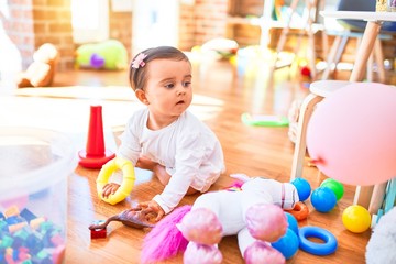Beautiful infant happy at kindergarten around colorful toys