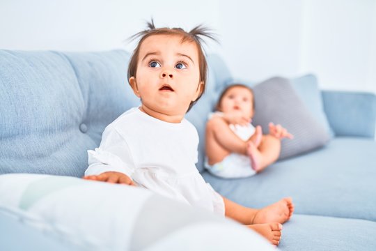 Beautiful infant happy girls playing together at home kindergarten sitting on the sofa
