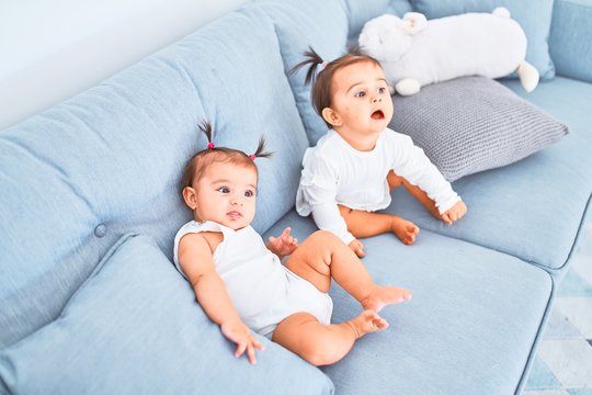 Beautiful infant happy girls playing together at home kindergarten sitting on the sofa