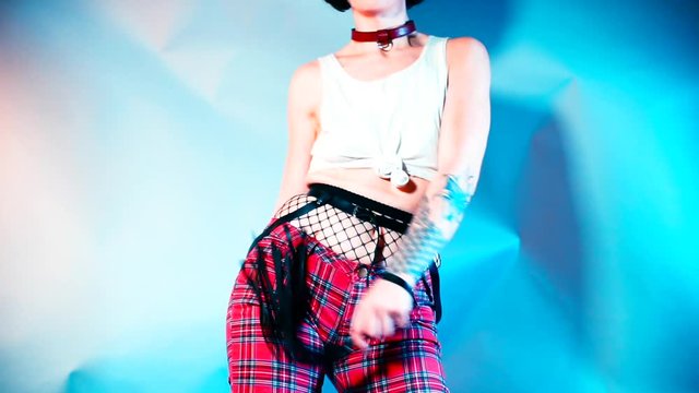 A girl in a suit makes dance moves at a kinky party. 