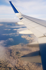 A large coastal city under the wing of an airplane