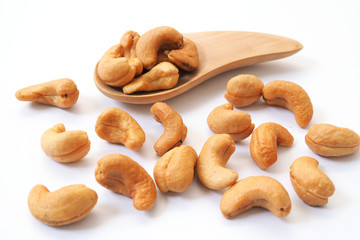 Dried cashews on a wooden spoon isolated on white background.