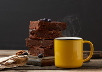 yellow ceramic cup with coffee and a stack of baked brownie pieces