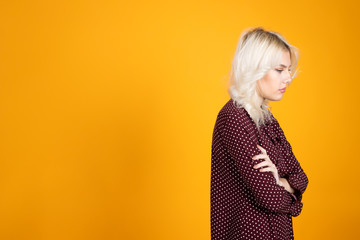 Offended blonde girl on yellow background