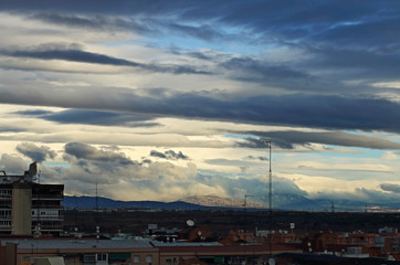 Fototapeta na wymiar A view of the mountains, with a cloudy sky and an antenna and rooftops