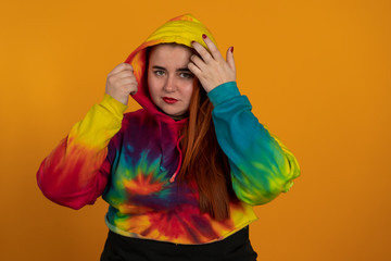 Smiling plus size girl in bright hoodie isolated on yellow background