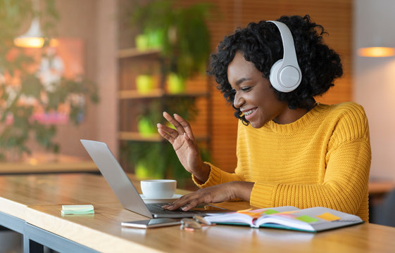 Afro girl in headset using laptop, having skype conference