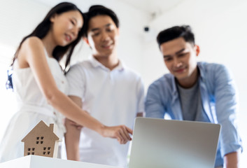 Asian couple Decide to buy a new house from laptop with Real estate agent, subject is a house model with key