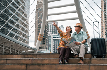 A couple of elderly Asian tourists visiting the capital happily and having fun and looking at the map to find places to visit.