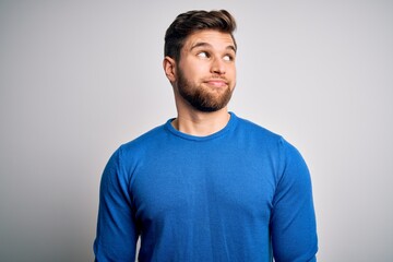 Fototapeta premium Young handsome blond man with beard and blue eyes wearing casual sweater smiling looking to the side and staring away thinking.