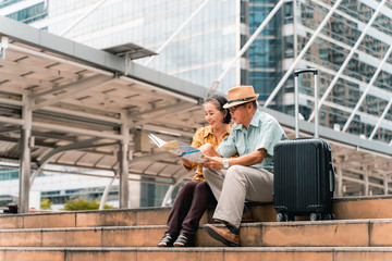 A couple of elderly Asian tourists visiting the capital happily and having fun and looking at the map to find places to visit.