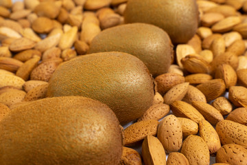 four kiwi lie on unpeeled almonds. natural background for healthy eating concept