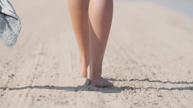 Young brunette woman in a bikini slowly walking along the shore. Slow motion.