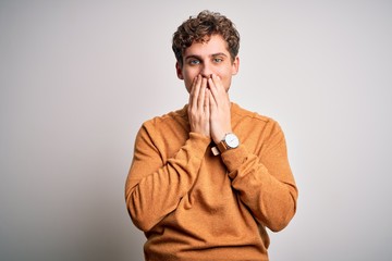 Young blond handsome man with curly hair wearing casual sweater over white background laughing and...
