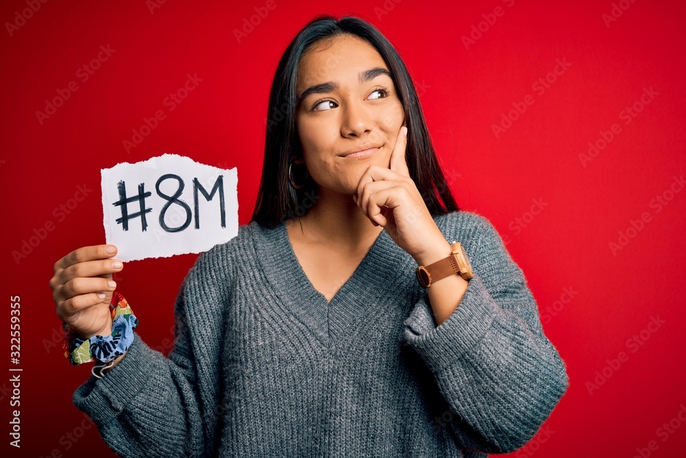 Poster Young beautiful asian woman celebrating 8th march womens day holding reminder paper serious face thinking about question, very confused idea