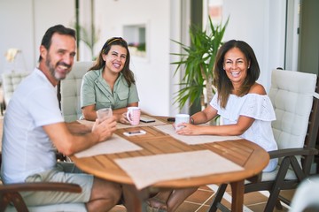 Beautiful family sitting on terrace drinking cup of coffee speaking and smiling