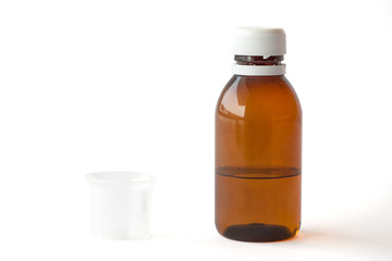 Bottle with Medicine and Measuring Cup on White