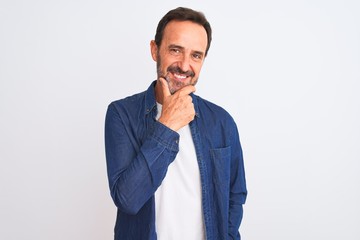 Middle age handsome man wearing blue denim shirt standing over isolated white background looking confident at the camera smiling with crossed arms and hand raised on chin. Thinking positive.