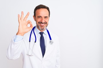 Middle age doctor man wearing coat and stethoscope standing over isolated white background smiling positive doing ok sign with hand and fingers. Successful expression.