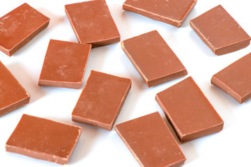 Milk chocolate pieces isolated on white background from top side view