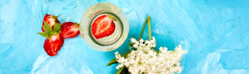 Banner of Kombucha tea with elderflower and strawberry on blue background.
