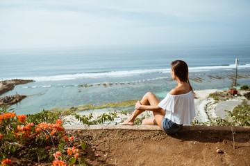 Outdoor summer portrait of young pretty woman looking to the ocean at tropical beach