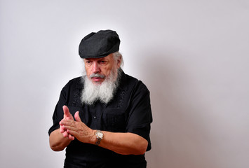 Old man deep in thought  .. .Mature gentleman with a newsboy cap and black guayabera shirt and long white beard..