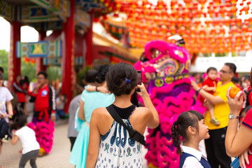 Chinese New Year celebration in a Chinese temple. A Chinese dragon dances and distributes sweets and tangerines. Festive Chinese entertainment