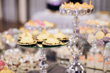 Yellow sweet cakes on a festive dessert table in a restaurant. Wedding dessert