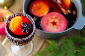 Mulled wine in a beautiful glass next to the saucepan. Hot drink in a glass. Christmas concept. Family evening with a hot drink. We cook mulled wine with apples and oranges. Hot wine.