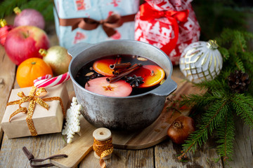 Christmas red wine mulled wine with spices and fruits on a wooden table. Winter concept. Traditional hot drink for Christmas. Mulled wine with citrus, apples and spices in a pan. Autumn concept.