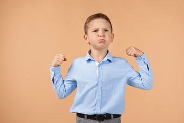 little boy shows his biceps on beige background. child showing his muscles