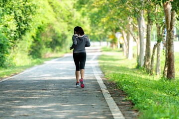 Fototapeta premium Healthy woman jogging run and workout on road outdoor. Asian runner people exercise gym with fitness session, nature park background. Healthy and Lifestyle Concept.