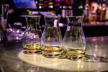 Flight of Scottish whisky, tasting glasses with variety of single malts or blended whiskey spirits on distillery tour in pub in Scotland