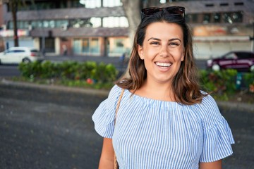 Young beautiful woman smiling happy walking on city streets on a sunny day of summer