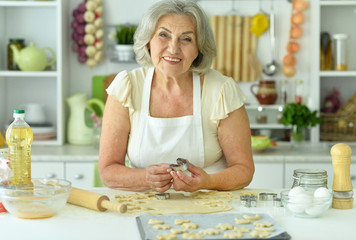 Portrait of senior woman baking delicious cookies