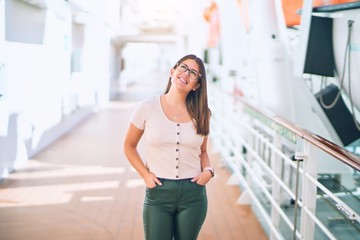 Young beautiful woman on vacation smiling happy and confident. Standing on a deck of ship with smile on face doing a cruise