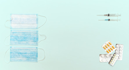 Medical masks, pills and syringes lie on a sky blue background top view. Recommendation of protection against coronavirus viruses and prevention and treatment of colds.
