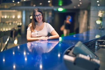 Young beautiful woman smiling happy and confident. Sitting with smile on face leaning on the counter bar at restaurant