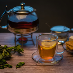 Cup of tea with teapot on a wooden table.