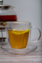 Cup of tea with teapot on a wooden table.
