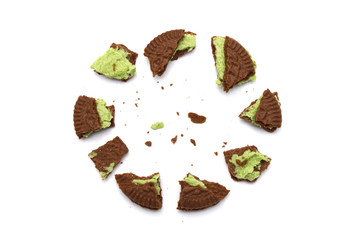 Crumbs of Chocolate sandwich cookies  filled with matcha green tea flavoured cream close-up isolated on white background.