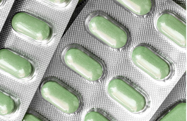 Several of blisters with colored green tablets close-up