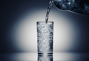 pouring sparkling water in a glass on a dark blue background