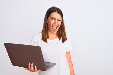 Beautiful young woman working using computer laptop over white background winking looking at the camera with sexy expression, cheerful and happy face.
