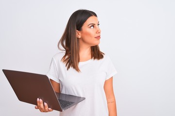 Beautiful young woman working using computer laptop over white background looking to side, relax profile pose with natural face and confident smile.